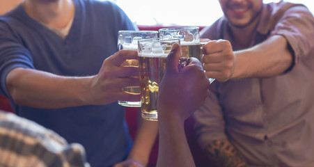 Cropped image of mates clinking beer glasses