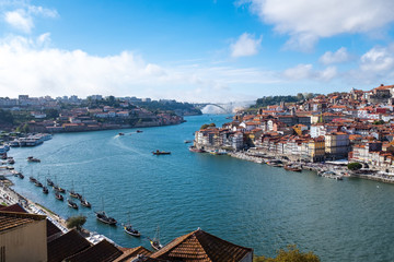 Obraz premium View of the Douro River snaking through the city of Porto from the Ponte Luiz bridge with traditional boats tied up on the river