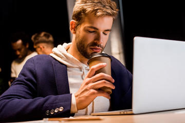 exhausted businessman drinking coffee to go while working at night in office