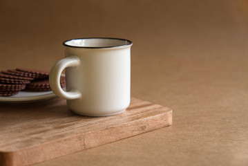 A white Cup of coffee stands on a wooden Board. brown background. copy space.