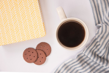 A white Cup of coffee, book and Chocolate cookies stands on a white background. flat lay. the view from the top.