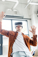 young businessman gesturing while using vr headset in office