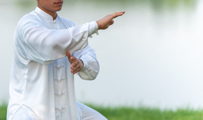 Asian man working out with Tai Chi in the morning at the park, Chinese martial arts, healthy care for life concept.