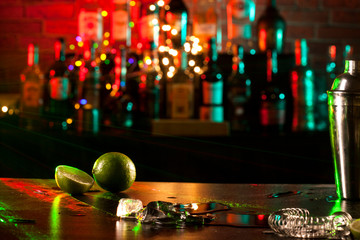 Bar counter with lime, ice cubes and shaker