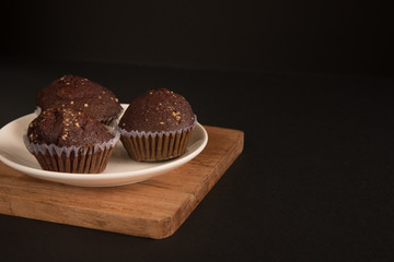 Sweet cupcaks with on dark black background. Chocolate muffins in white paper cups. Party food concept.