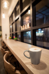 Hot cappuccino in a blue cup, put on a wooden table