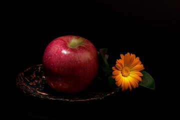 red apple and orange flower on a gold plate