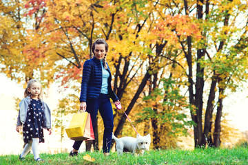 Happy family with dog on walk in autumn city park. Little daughter and mother going shopping. Family, pet, domestic animal concept