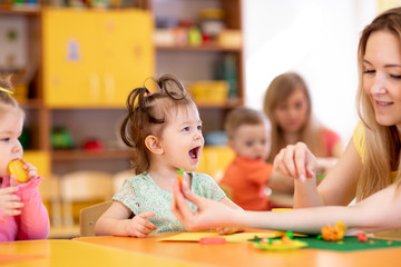 Children creativity. Kids sculpting from clay. Cute little girl with friends mould from plasticine on table in kindergarten