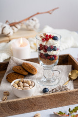 Homemade dessert with fresh blueberry, red currants, pistachios and cream cheese in glass. Cozy autumn dessert