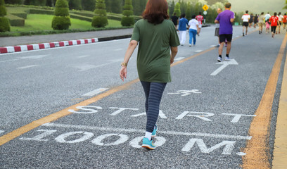 Closeup of Asian woman walking in running track  on the road of public park.