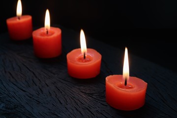 Fototapeta na wymiar Burning red candles on black wooden background