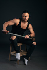 young bodybuilder in black clothes with a sledgehammer in his hands. Studio photography