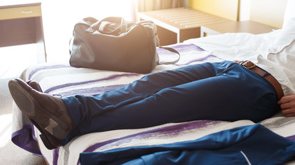 Man legs in formal trousers, resting on hotel bed
