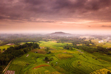 Fototapeta na wymiar Indonesian natural beauty with aerial photography at sunrise on the mountains in yellow and green with beautiful sky on moment