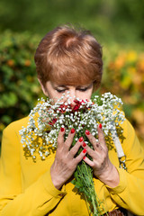 Elderly woman with a bouquet of flowers. A pensioner woman is holding a bouquet of flowers in her hands, a gift from her husband.