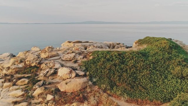 Zoom aerial drone shot of ocean view panorama from rocky cliff with view of horizon and ocean line, with mountains chains in the distance