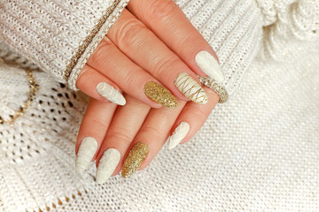 Knitted sand manicure on long oval nails with golden sequins and threads on the female red in a...