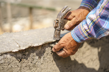 Worker labor hitting building concrete wall