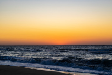 Sunrise over the Black sea, waves on the sandy beach.
