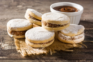 Traditional Argentinian alfajores with dulce de leche and sugar on wooden table