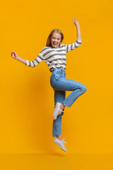 Fototapeta na wymiar Positive beautiful teen girl jumping in air with hands up