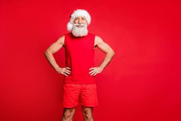 Portrait of cheerful santa claus cap putting his hands on waist true coach wearing sports wear isolated over red background