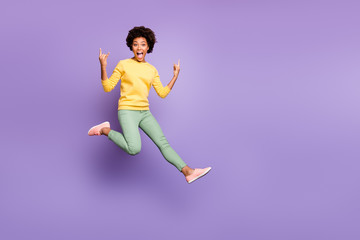 Fototapeta na wymiar Lets rock. Full size photo of cheerful crazy girl fool on autumn spring holiday show horns true rocker sign wear yellow pullover green pants trousers isolated purple violet color background