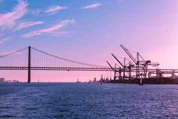 Pink purple sky over the Bay of Lisbon, port and bridge, marine industrial landscape