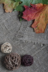 Colorful autumn leaves on a background of rough linen cloth. Near rattan balls.