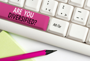 Conceptual hand writing showing Are You Diversified Question. Concept meaning someone who is Different Mixed Multi Faceted White pc keyboard with note paper above the white background