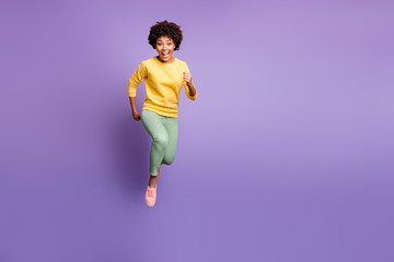 Fototapeta na wymiar Discounts i come. Portrait of funky crazy afro american girl jump run hurry get autumn black friday bargain wear yellow sweater green pants trousers sneaker isolated violet purple color background
