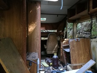 Ancient camper abandoned in autumnal foliage in natural light