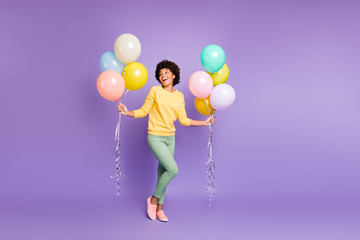 Fototapeta na wymiar Full length photo of positive cheerful dark skin girl feel funky emotions laugh on spring valentine day hold baloons wear green jumper green pants trousers isolated purple violet color background