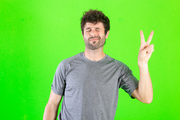 caucasian crazy man making funny symbols over green background