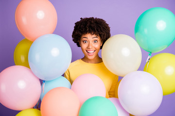 Fototapeta na wymiar Photo of cheerful positive wavy cute nice charming black girl surrounded with air balls smiling toothily isolated over violet pastel color background