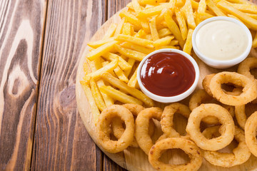 French fries and onion rings with sauces