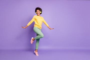 Fototapeta na wymiar Full length body size turned photo of cheerful positive cute nice charming girlfriend dancing in headphones wearing yellow sweater green pants trousers isolated over violet pastel color background