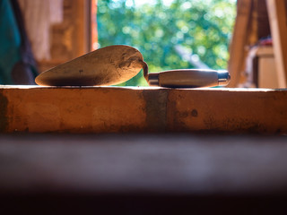 The stove trowel was left on an unfinished brick oven.