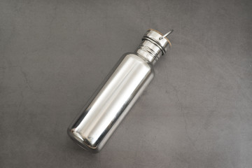 Durable, high quality reusable stainless steel bottle on gray background as alternative to plastic bottles. Toxin, BPA, plastic free zero waste option for drinking tap water at home or at the office.