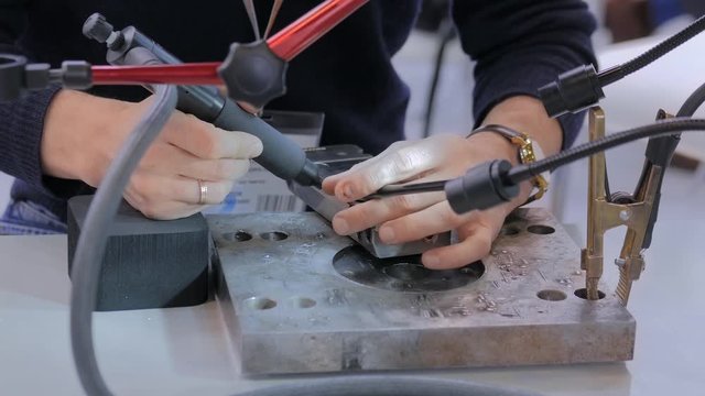 Professional male welder trying to work with gas tungsten arc welding (GTAW) or tungsten inert gas (TIG) technology at exhibition or trade show - close up view. Industrial concept and engineering work