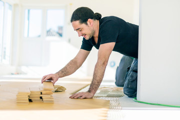 Carpenter on work putting wood parquet pieces. Home construction 