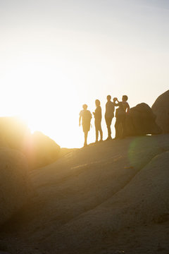 Silhouettes of people on rock at sunset