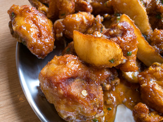 Close-up of Korean sauce deep fried chicken and potato wedges.