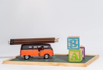 Back to school concept. school bus carry  pencils and letters block on blackboard