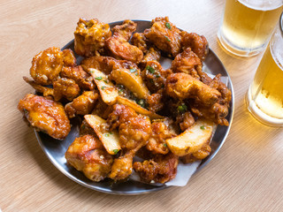 Korean sauce deep fried chicken and potato wedges served with beer.