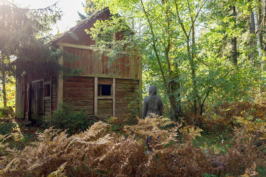 Woman wearing coat by barn in forest