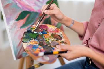 art, creativity and inspiration concept - close up of hands with paintbrush painting at home or studio