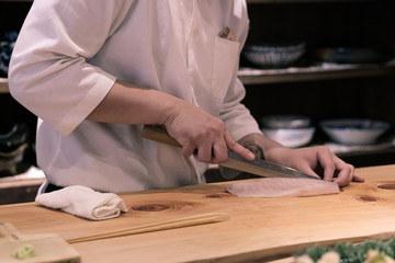 Chef preparing slicing raw fish for sushi at the counter-top, Omakase style Japanese traditional.