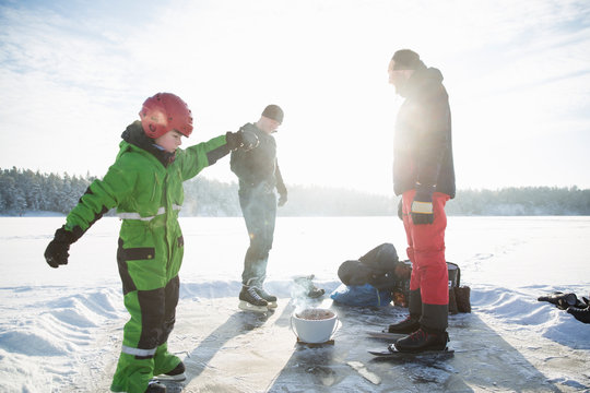 Boy and men with barbeque on frozen Drang lake in Uppland, Sweden